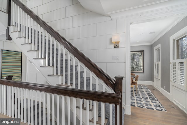 stairs with wood finished floors, baseboards, and ornamental molding