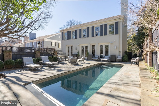 view of pool featuring french doors, fence, a fenced in pool, and a patio area