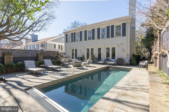 outdoor pool with a patio, french doors, and fence