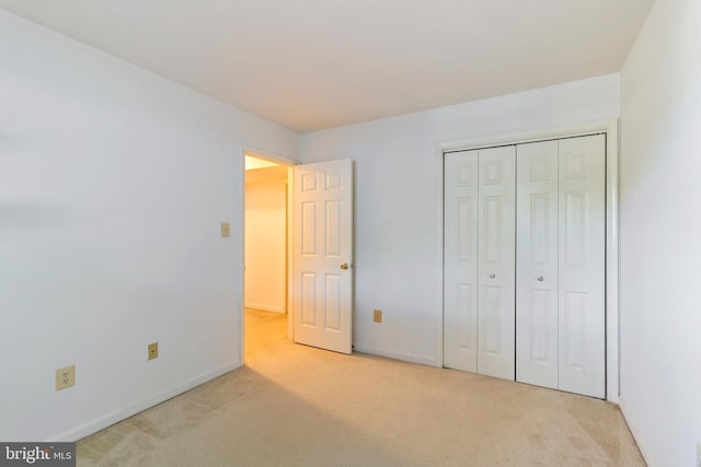 unfurnished bedroom with light carpet and a closet