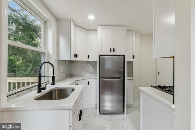 kitchen with white cabinetry, tasteful backsplash, stainless steel fridge, and sink