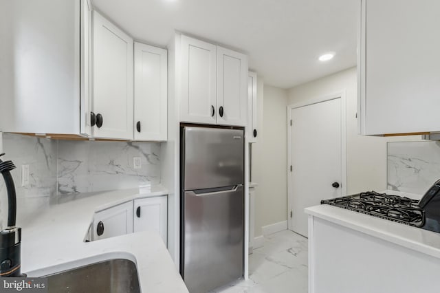 kitchen featuring stainless steel refrigerator, white cabinetry, decorative backsplash, and gas stovetop