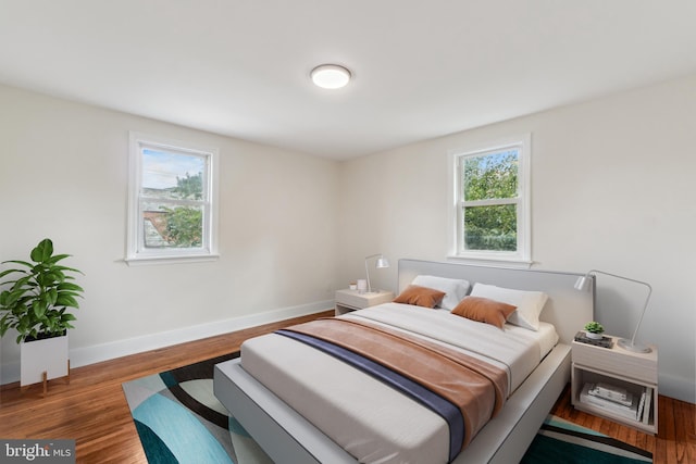 bedroom with multiple windows and dark hardwood / wood-style flooring