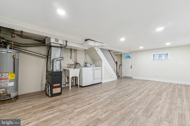 basement with washing machine and dryer, gas water heater, light hardwood / wood-style floors, and sink