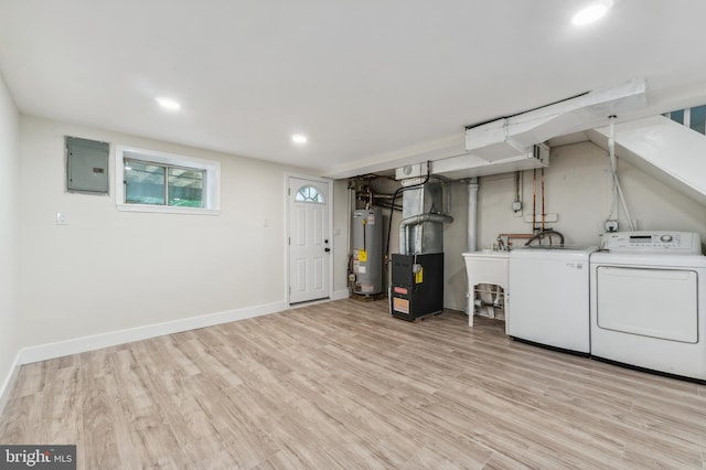 laundry area featuring washing machine and dryer, water heater, electric panel, heating unit, and light hardwood / wood-style floors