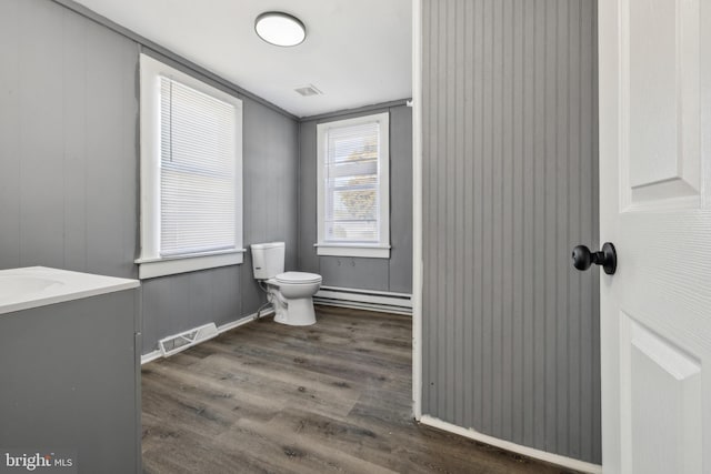 bathroom with toilet, vanity, wood-type flooring, and a baseboard heating unit