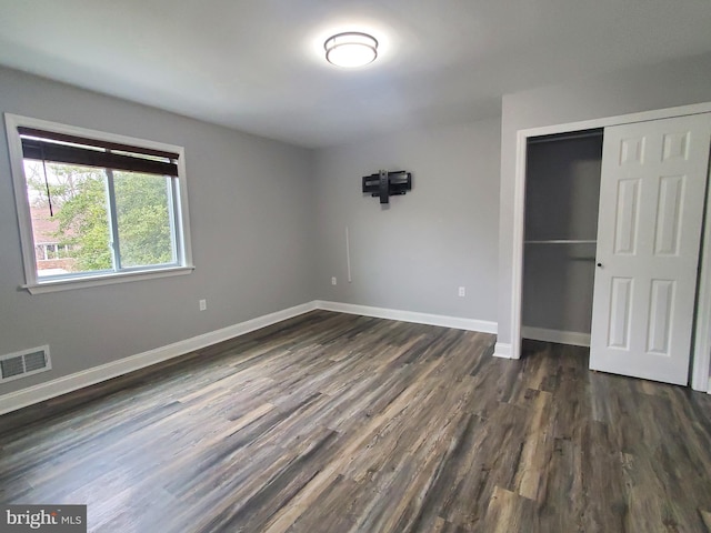 unfurnished bedroom featuring dark hardwood / wood-style flooring and a closet