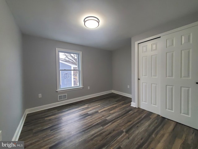 unfurnished bedroom with dark hardwood / wood-style flooring and a closet