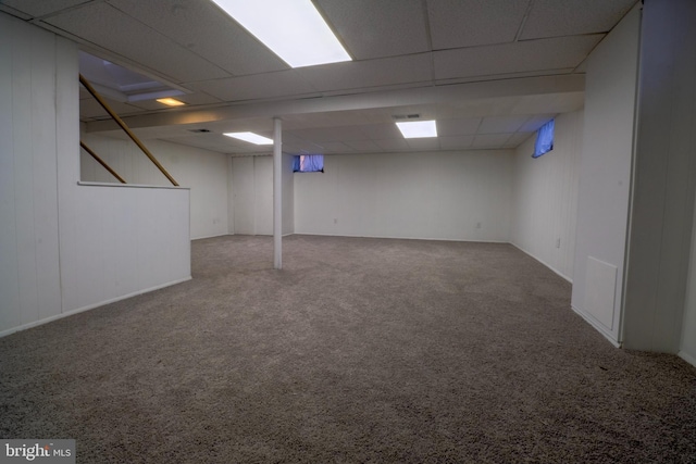 basement with a paneled ceiling and carpet floors