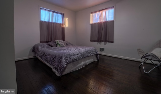 bedroom with dark hardwood / wood-style flooring and multiple windows