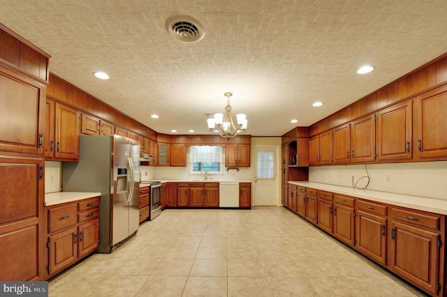 kitchen featuring pendant lighting, stainless steel appliances, a notable chandelier, and sink