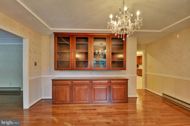 bar featuring decorative light fixtures, baseboard heating, a notable chandelier, and a tray ceiling