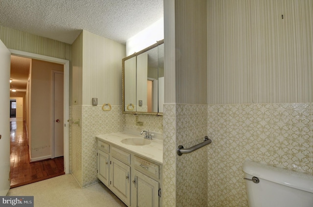 bathroom featuring vanity, a textured ceiling, and toilet