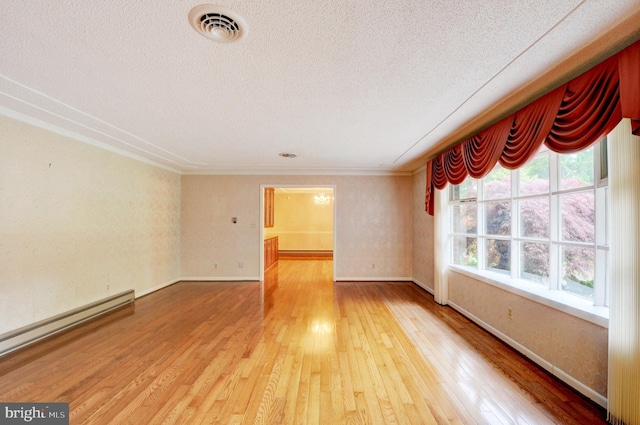 spare room with baseboard heating, wood-type flooring, and a textured ceiling