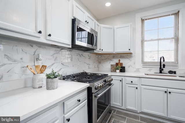 kitchen featuring sink, white cabinetry, stainless steel appliances, and tasteful backsplash