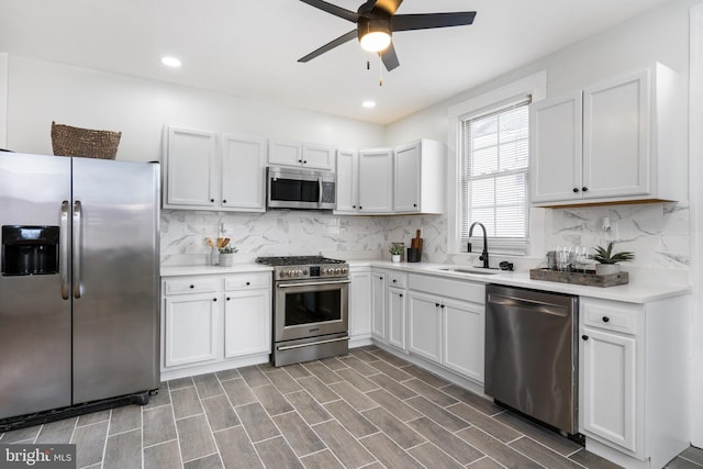 kitchen with sink, ceiling fan, appliances with stainless steel finishes, tasteful backsplash, and white cabinetry