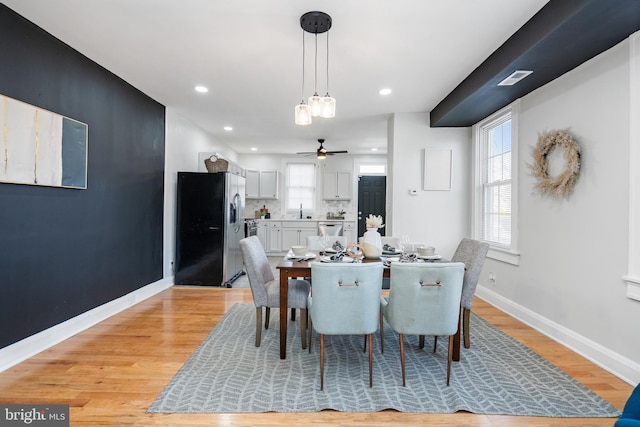 dining space with ceiling fan, light hardwood / wood-style flooring, and sink