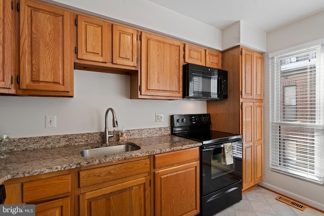 kitchen with sink, light stone counters, and black appliances