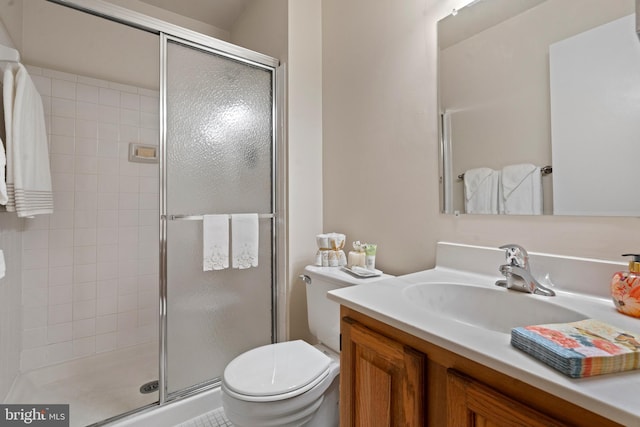 bathroom featuring a shower with door, toilet, and vanity