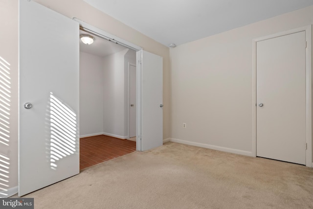 unfurnished bedroom with light colored carpet and a closet