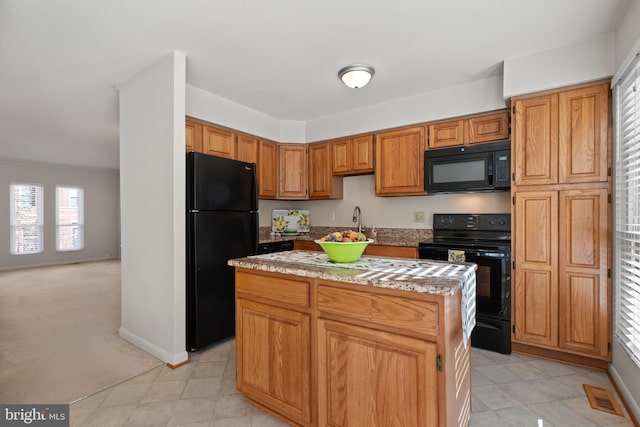 kitchen with a kitchen island, light colored carpet, and black appliances