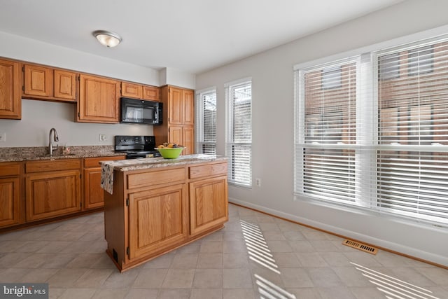 kitchen featuring black appliances, plenty of natural light, sink, and a kitchen island