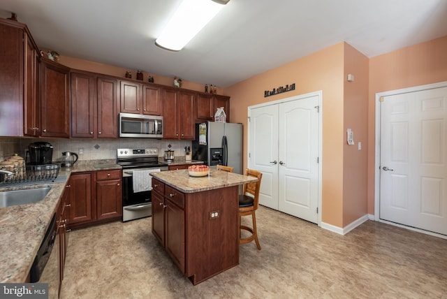 kitchen featuring light stone countertops, sink, a kitchen island, and appliances with stainless steel finishes