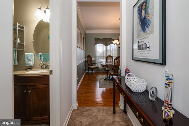 hall featuring a chandelier, hardwood / wood-style flooring, crown molding, and sink