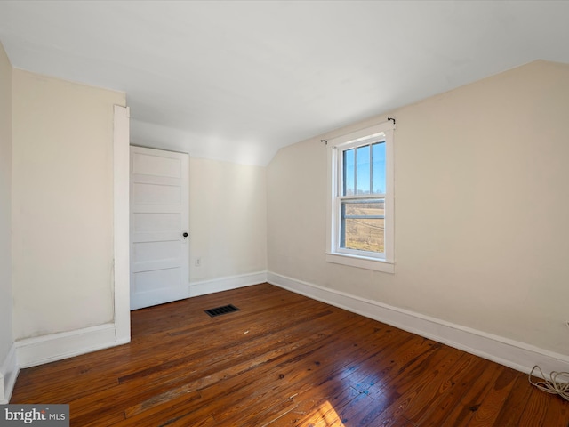 spare room featuring dark wood-type flooring and vaulted ceiling