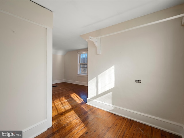 corridor featuring wood-type flooring and vaulted ceiling