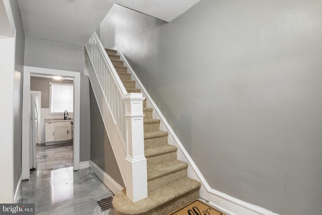 stairway featuring sink and concrete flooring