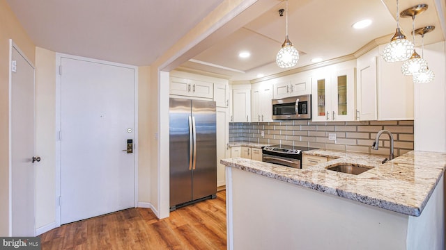 kitchen featuring sink, white cabinetry, decorative light fixtures, stainless steel appliances, and light stone countertops