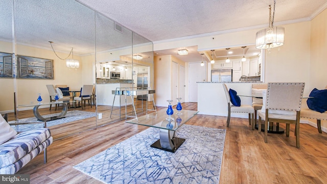 living room featuring crown molding, light hardwood / wood-style floors, and a textured ceiling