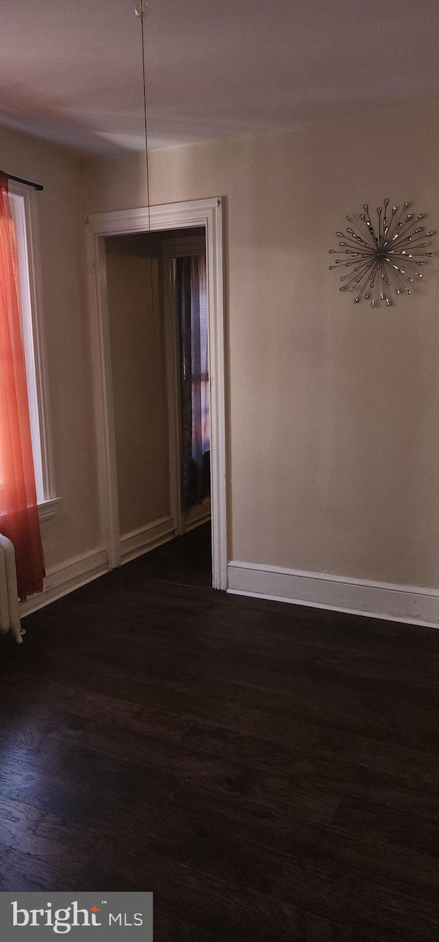 empty room with dark hardwood / wood-style floors and radiator