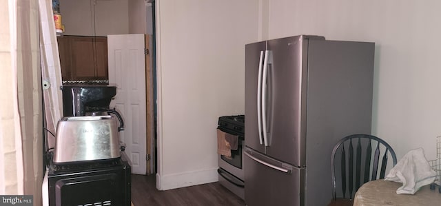 kitchen featuring dark wood-type flooring, stainless steel refrigerator, and range with gas cooktop