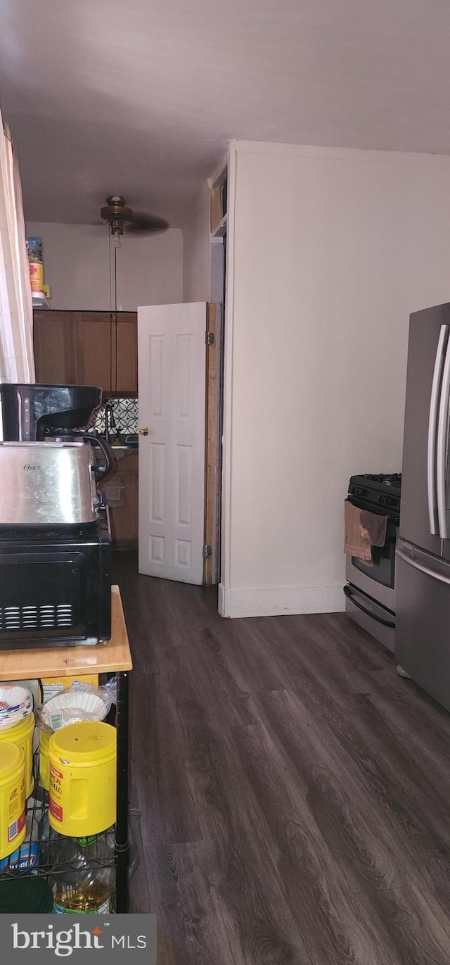 kitchen with stainless steel fridge, dark wood-type flooring, and range with gas stovetop