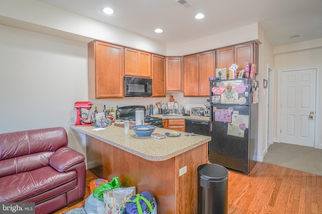 kitchen featuring kitchen peninsula, light wood-type flooring, sink, and black appliances