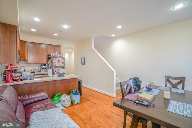 kitchen featuring stainless steel refrigerator, kitchen peninsula, and light wood-type flooring