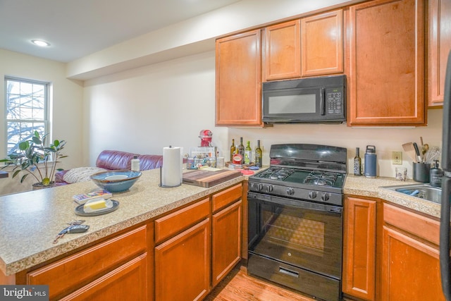 kitchen featuring black appliances, light hardwood / wood-style floors, and kitchen peninsula