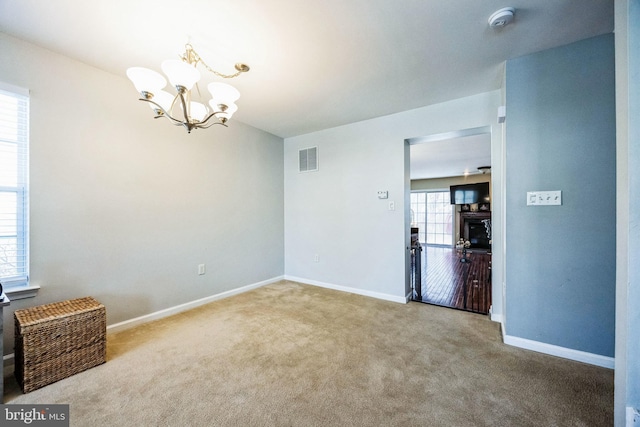 carpeted spare room with a chandelier