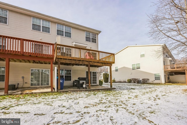 snow covered property featuring a deck, a patio, and central air condition unit