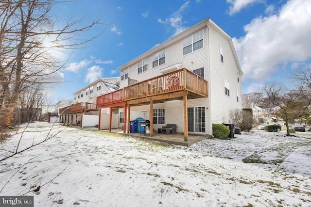 snow covered house with a patio and a deck