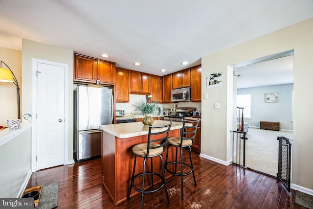 kitchen featuring a breakfast bar, a kitchen island, dark hardwood / wood-style flooring, and appliances with stainless steel finishes