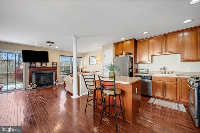 kitchen with a kitchen breakfast bar, dark hardwood / wood-style flooring, stainless steel appliances, sink, and a kitchen island