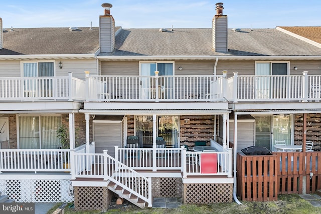 rear view of property featuring covered porch, brick siding, and a chimney