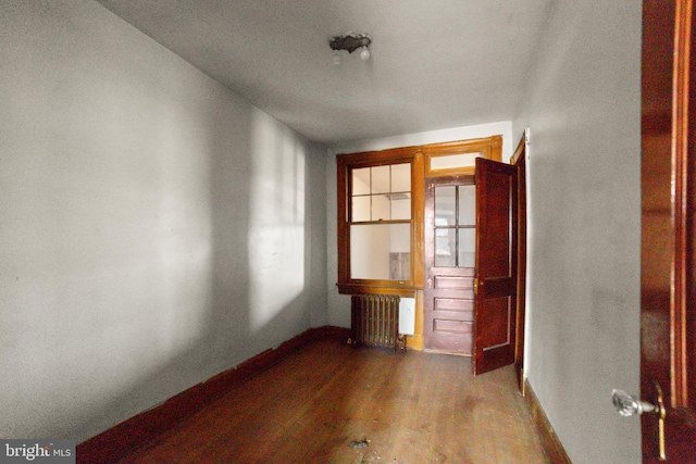 empty room with radiator heating unit and hardwood / wood-style floors