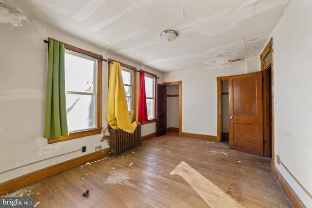 unfurnished room featuring radiator and hardwood / wood-style floors