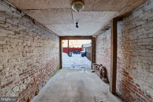 hallway featuring brick wall, wooden ceiling, and concrete floors