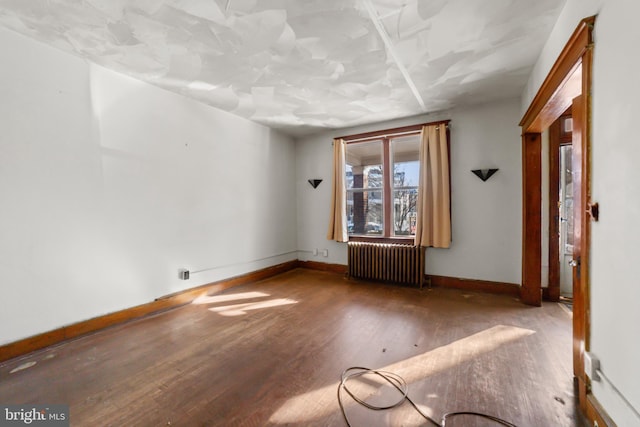 spare room featuring radiator heating unit and hardwood / wood-style flooring