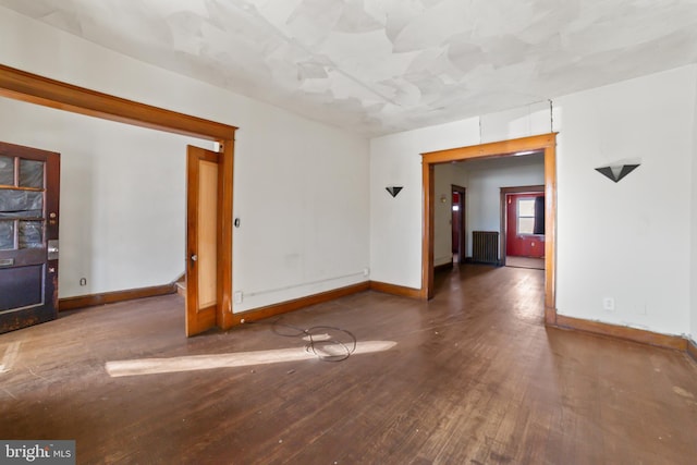 empty room featuring radiator and dark hardwood / wood-style flooring